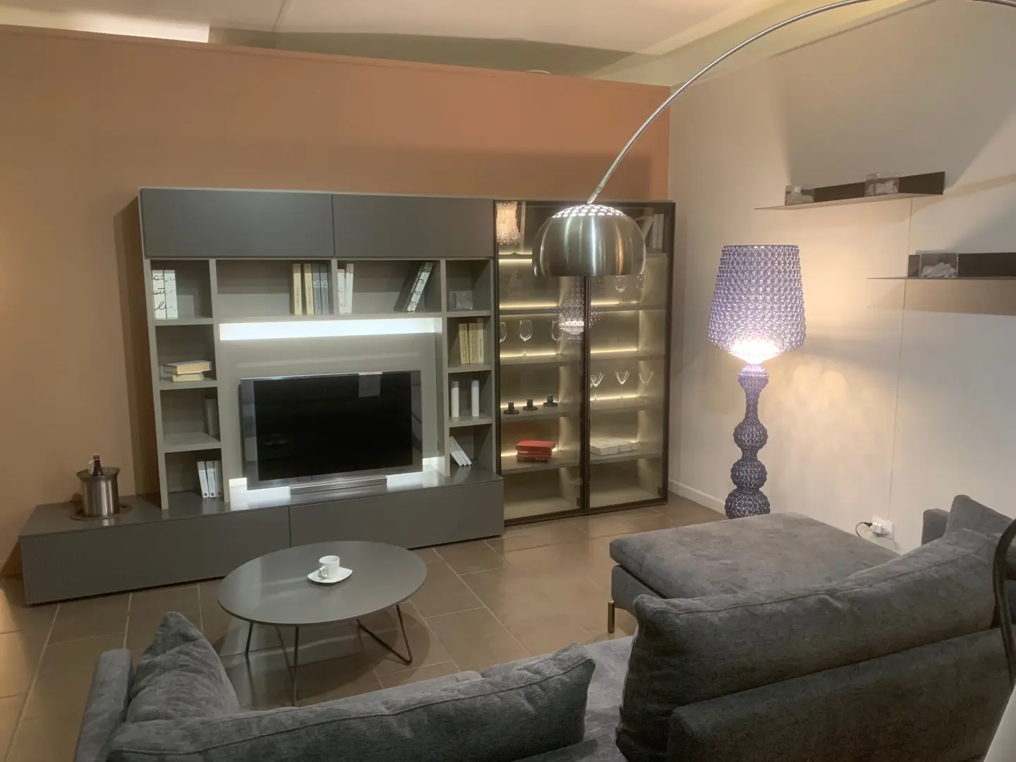 Composizione soggiorno Novamobili in laccato grigio con mobile TV, vani a giorno, pensili e vetrina illuminata, esposta nello showroom Arredamenti Soldi a Follonica